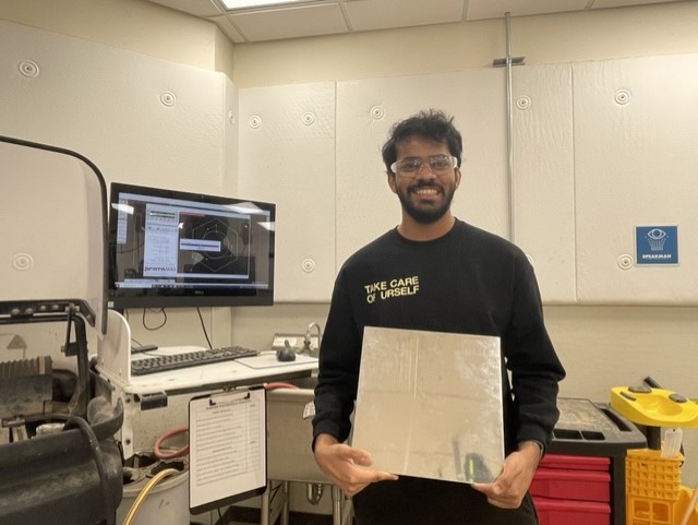 Josh holding the stainless steel sheet before cutting the corner damper cases.